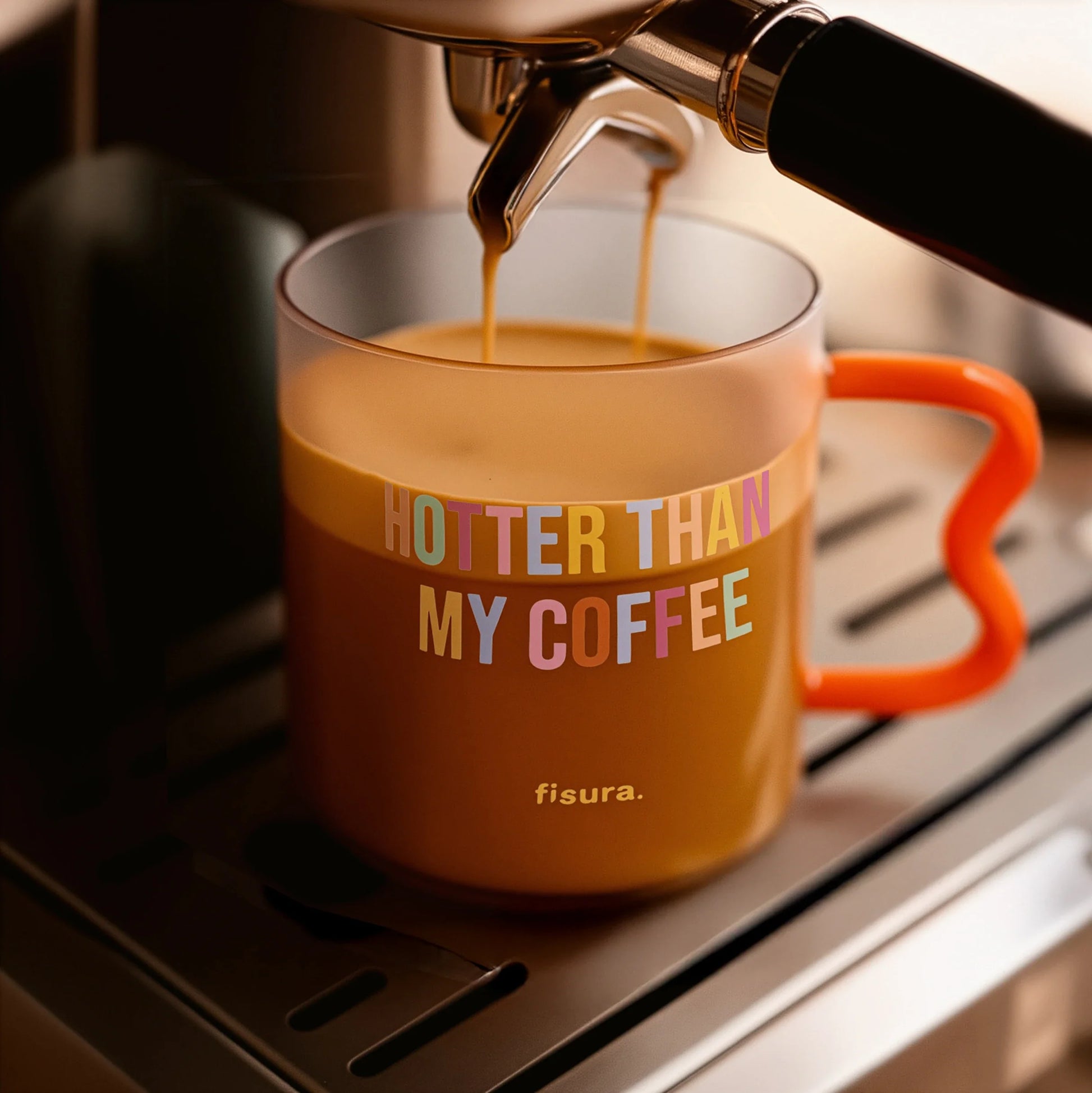Coffee being poured into the glass mug on a dark worktop