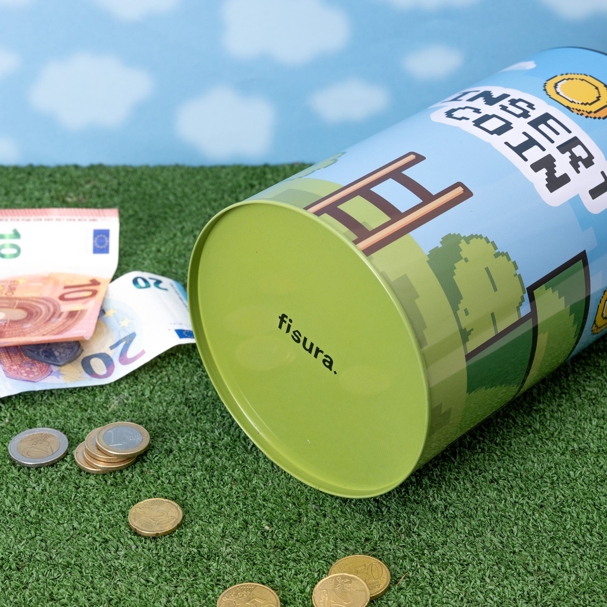 Insert Coin tin lying on its side with coins and notes scattered around