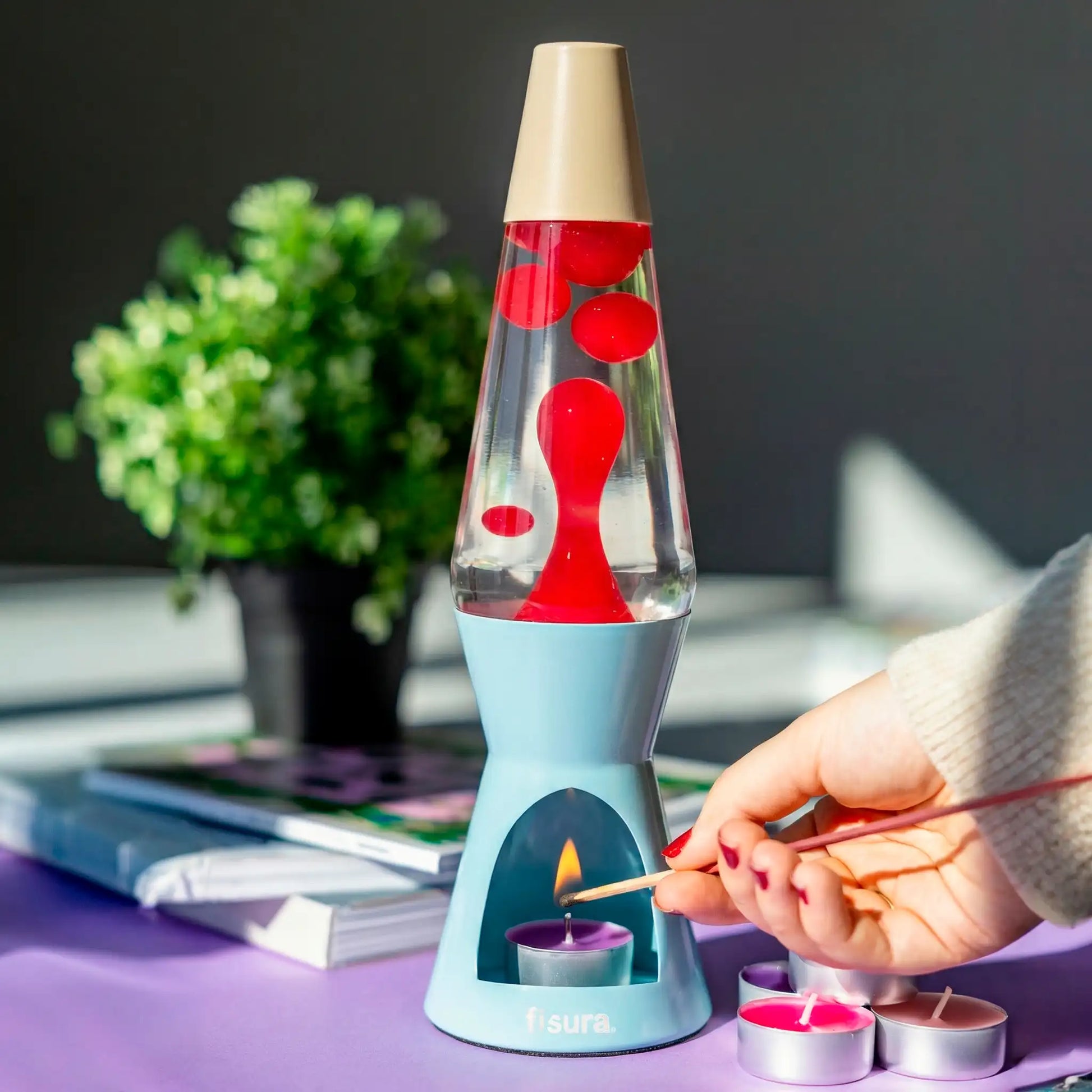 Hand placing a tealight under the blue lava candle lamp on a purple desk