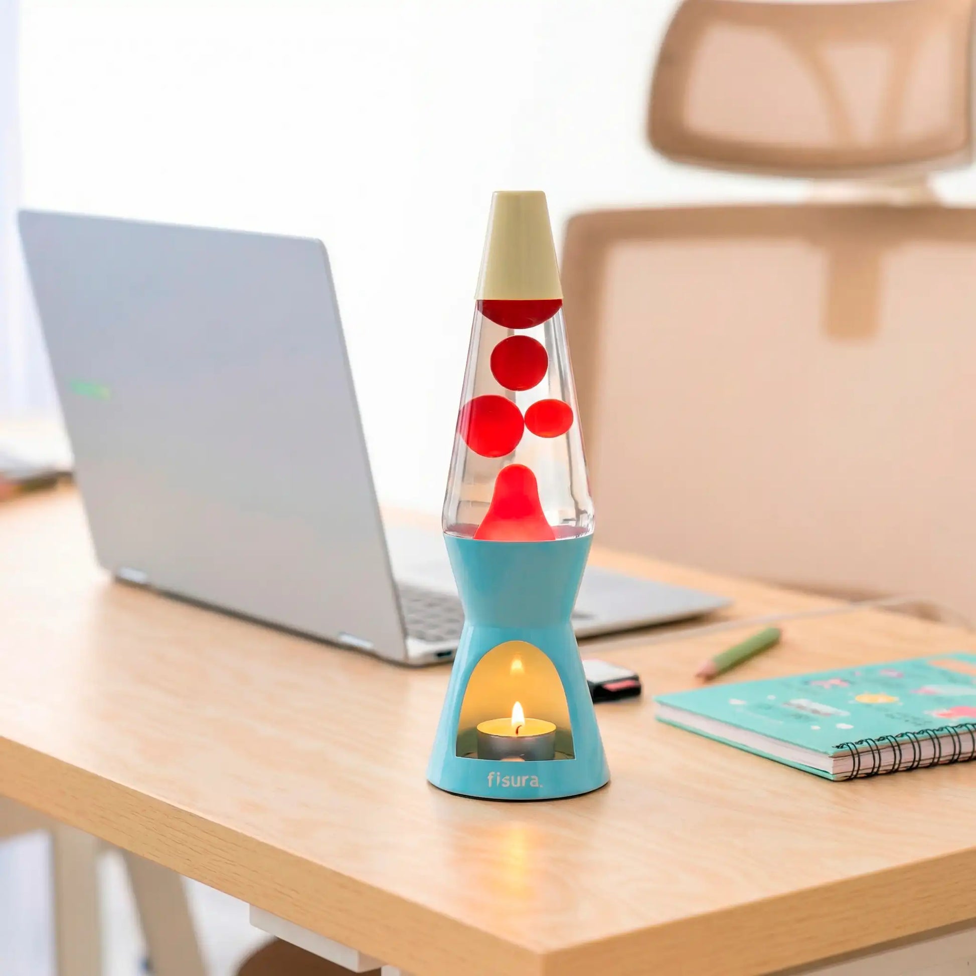 Blue lava candle lamp on a wooden desk beside an open laptop