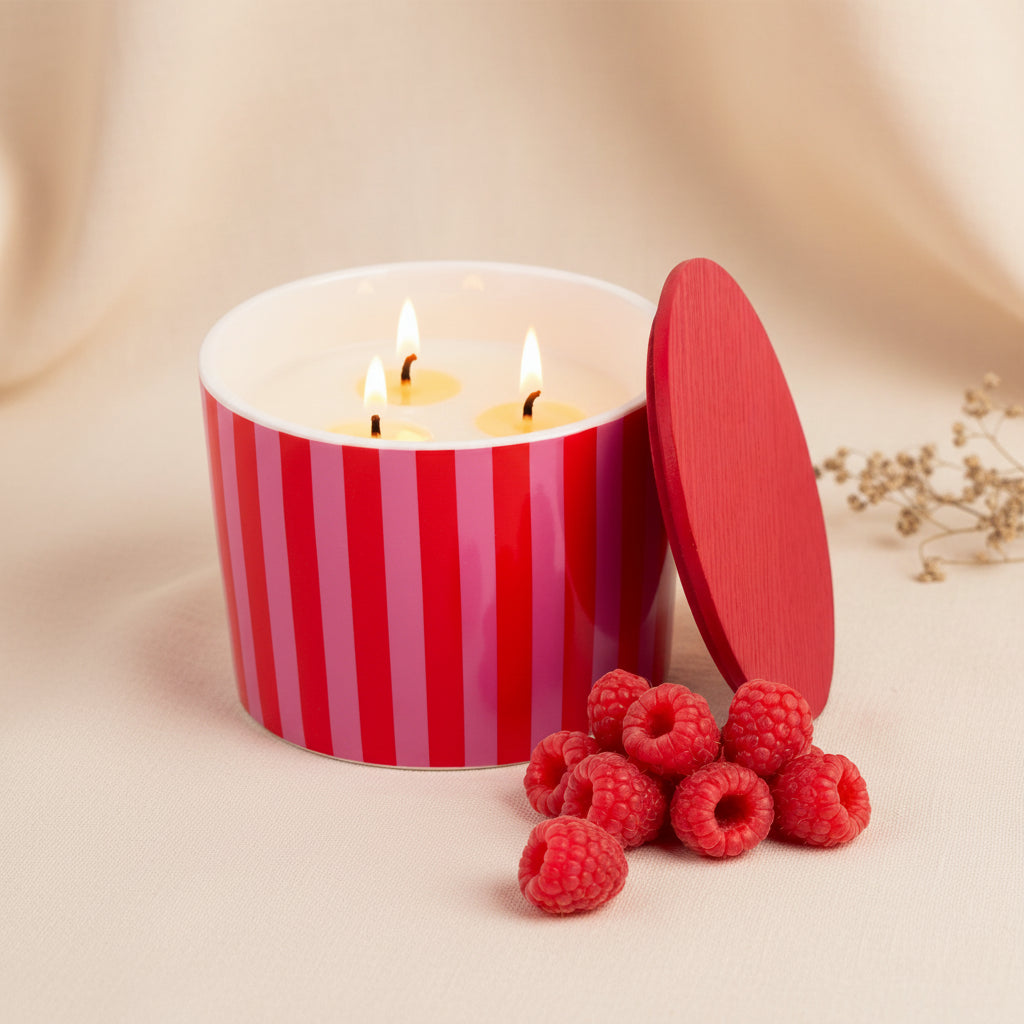 Striped ceramic raspberry candle with its wooden lid resting alongside