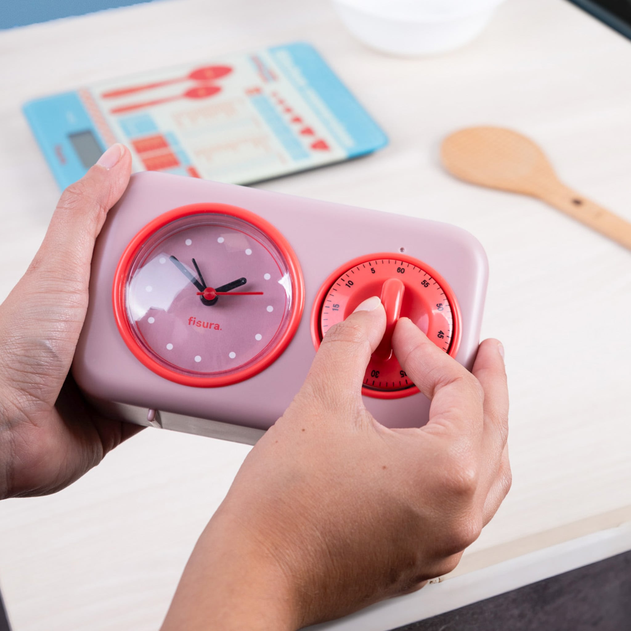 Hands turning the countdown dial on the pink retro kitchen timer