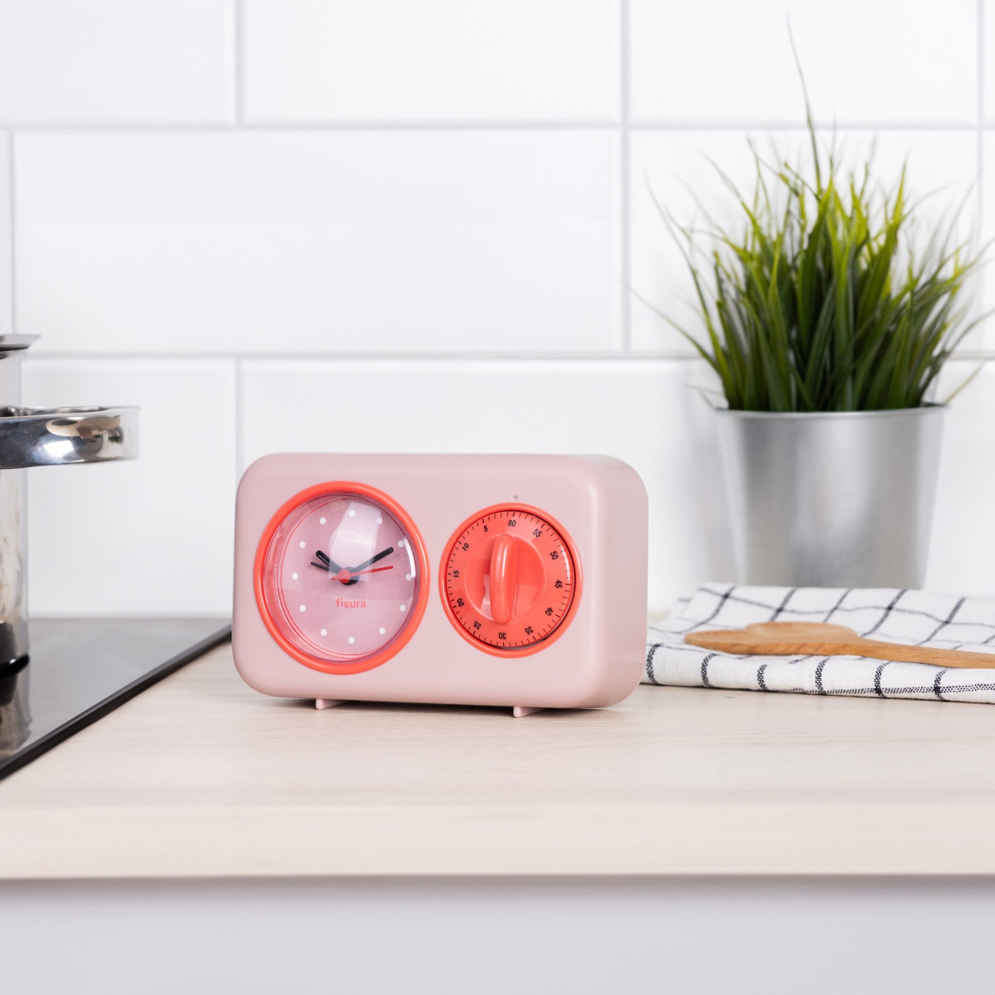Pink retro kitchen timer on a worktop beside a plant and a chopping board