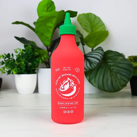 Red chilli sauce bottle lamp on a white shelf with plants