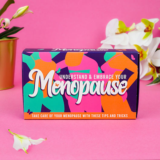 Menopause Cards gift box on a pink background with white flowers