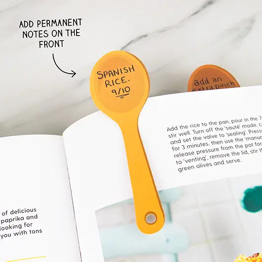 Orange spoon page marker with a recipe note marking a cookbook page