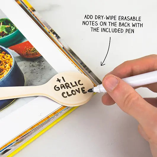 Writing a note on a Recipe Keepers spoon marker in a cookbook