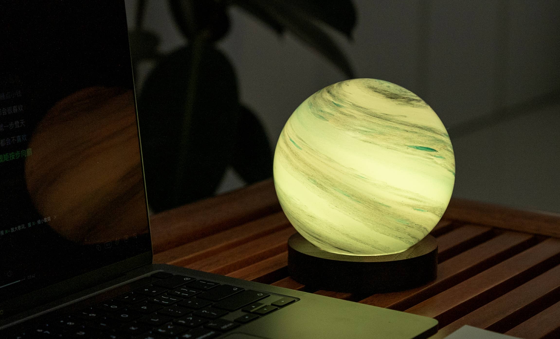 AstraGlass light shining pale green next to a laptop at night