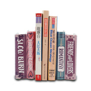 Pair of ceramic bookends shaped like stacked romantasy paperbacks holding books