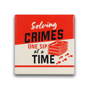 Red square ceramic coaster reading Solving Crimes One Sip At A Time with books