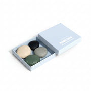 Boxed set of four pebble soaps on a white background