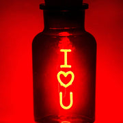 Red I Love You neon-style LED light glowing inside a clear glass bottle with a cork stopper.
