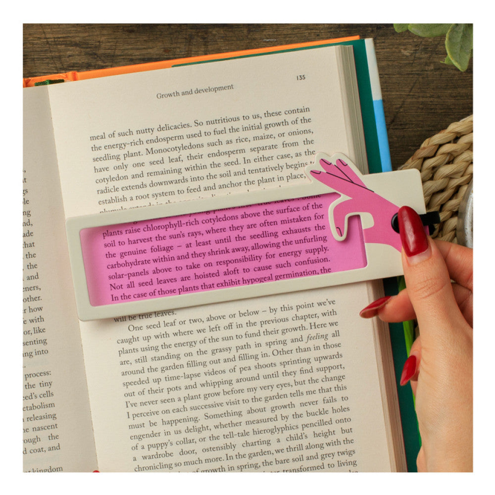 Hand sliding a pink reading aid bookmark down a printed page