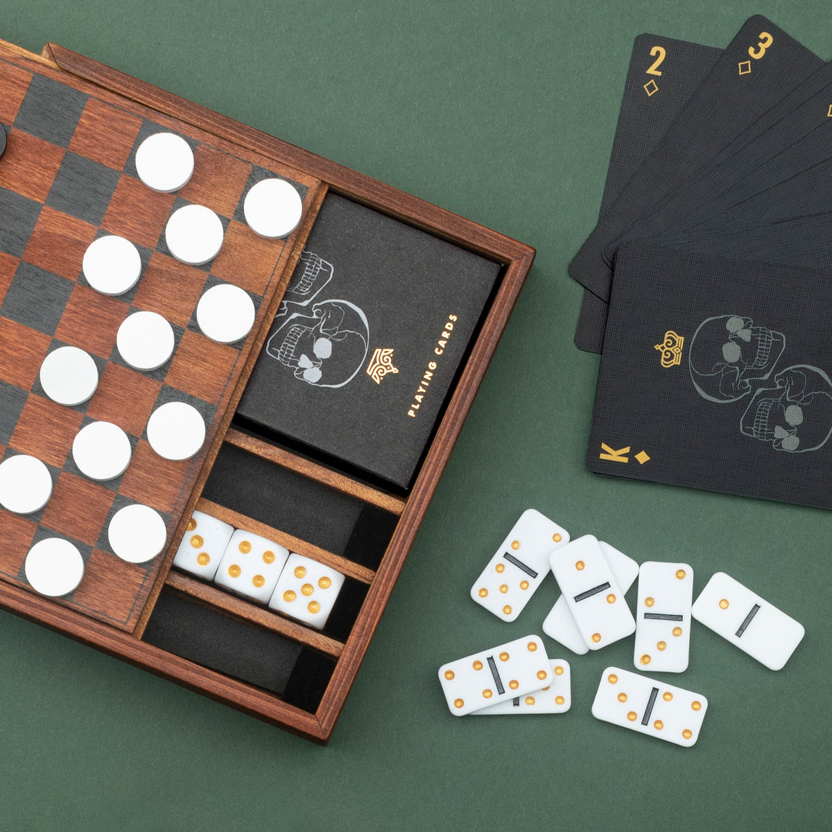 Games Night set with checkers, skull playing cards and dominoes on green
