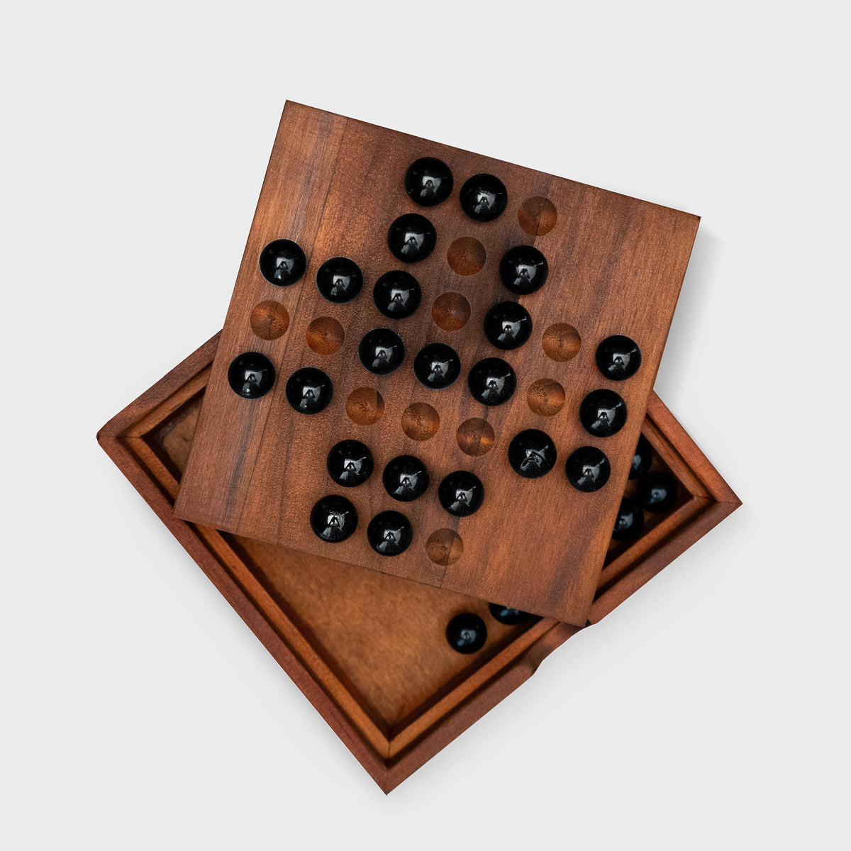 Solitaire board lid resting on its open wooden box, grey background