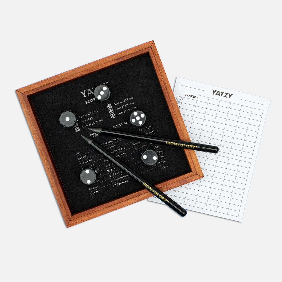 Yatzy wooden dice tray with black dice, pencils and score sheet on grey