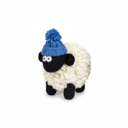 Knitted wool sheep in a blue bobble hat styled on a shelf