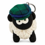 Knitted wool sheep keyring in a blue-green tartan flatcap, on a plain white background.