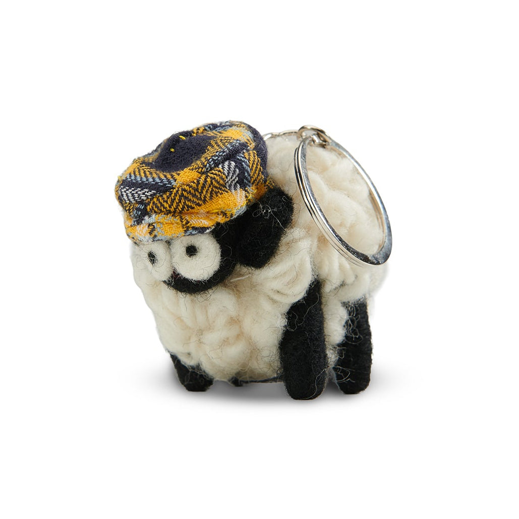 Knitted wool sheep keyring in a yellow tartan flatcap, on a plain grey background.
