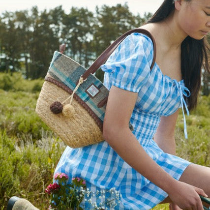 Woman on a bicycle carrying the Islander check straw basket bag