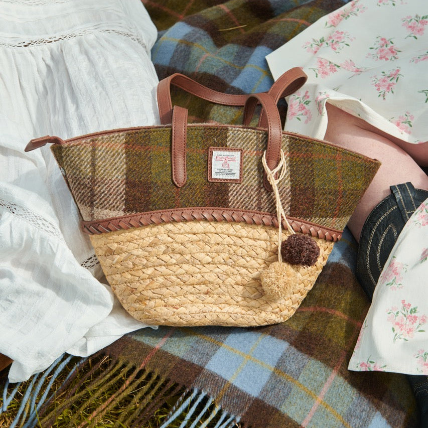 Basket bag carried on a picnic blanket alongside a Harris Tweed throw