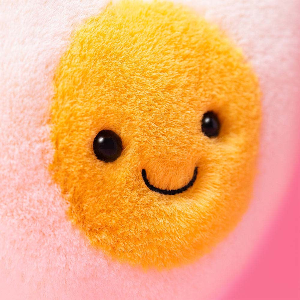 Close-up of the Heart Boiled Egg's smiling golden yolk face on a pink background