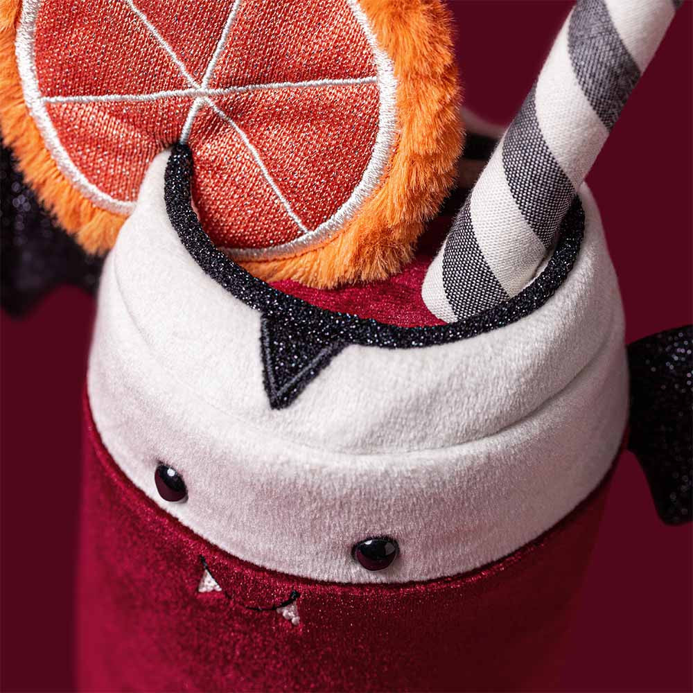 Close-up of Vampop Drink fangs, frothy top and orange slice on deep red