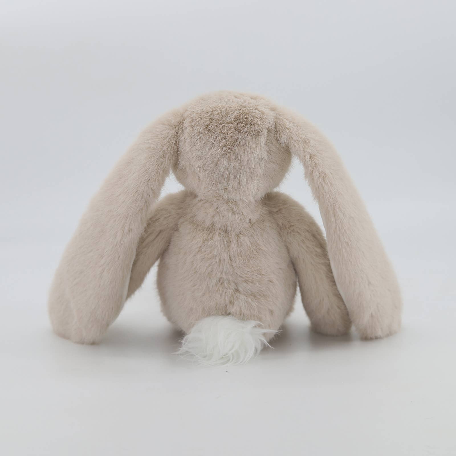 Back view of beige plush bunny showing fluffy white pom-pom tail