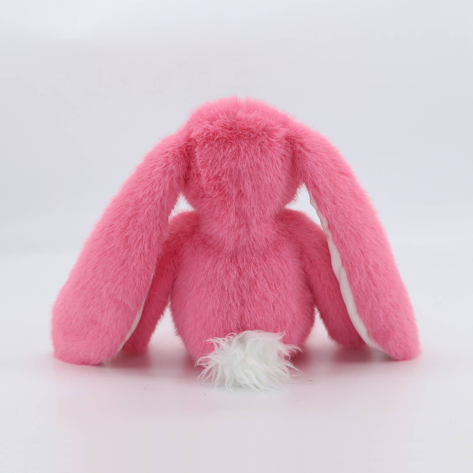 Back view of pink plush bunny showing fluffy white pom-pom tail
