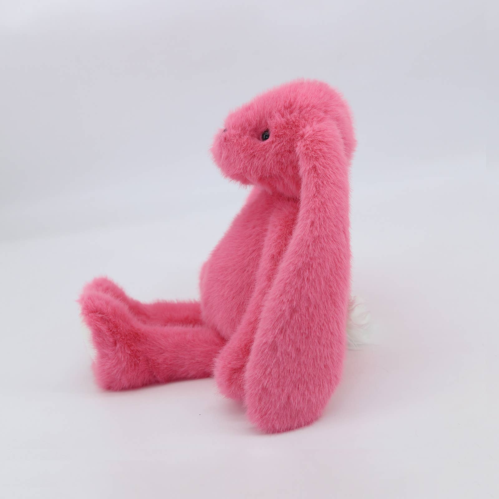 Pink plush bunny side profile showing long floppy ears and fluffy body