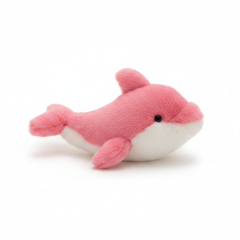 A pink and white plush shark toy resting on a cream-colored knit blanket with a wooden surface in the background.