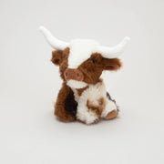 Texas Longhorn mini soft toy cow sitting with white horns on grey background