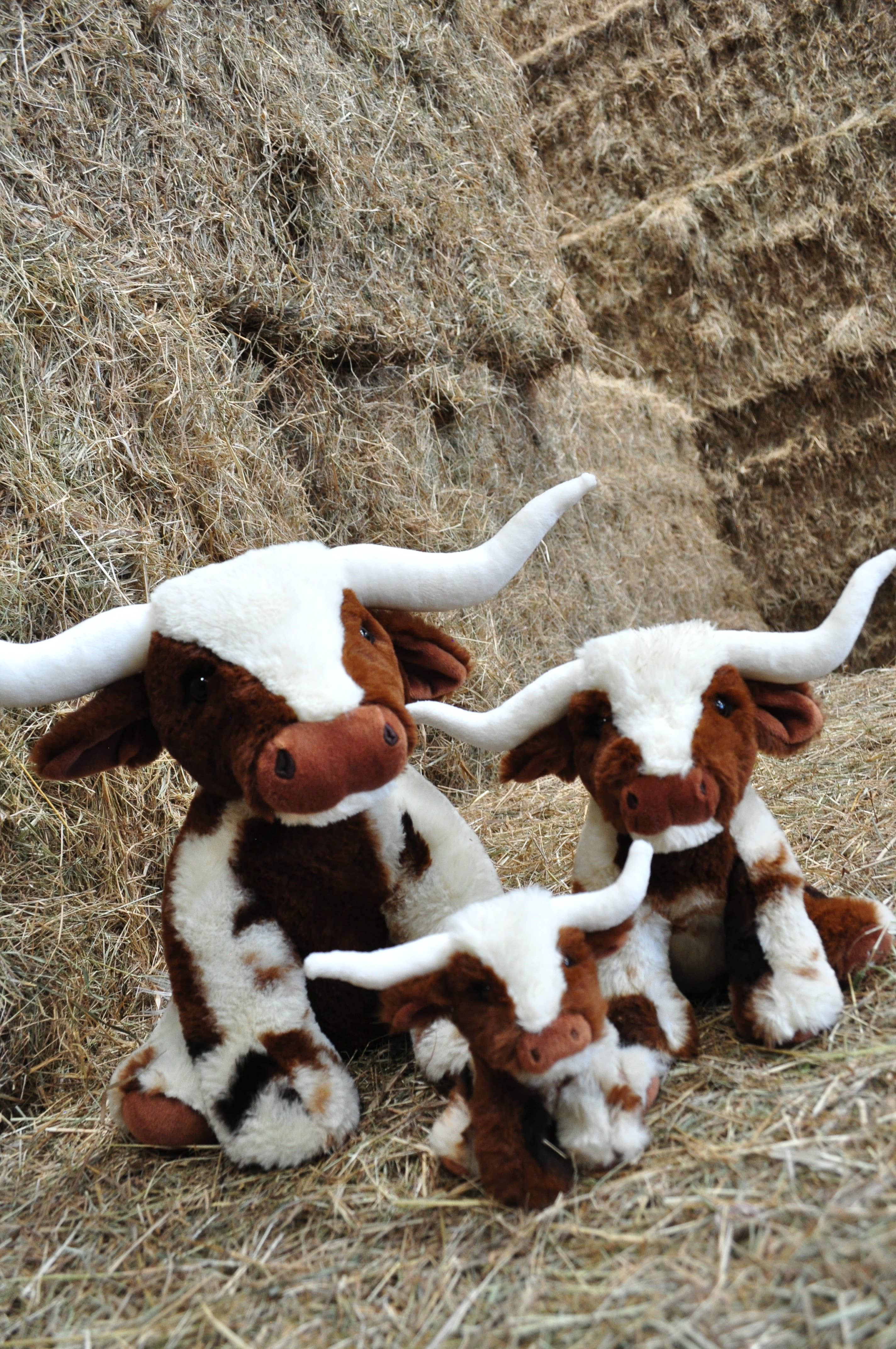 Texas Longhorn soft toy cows in three sizes posed on hay bales