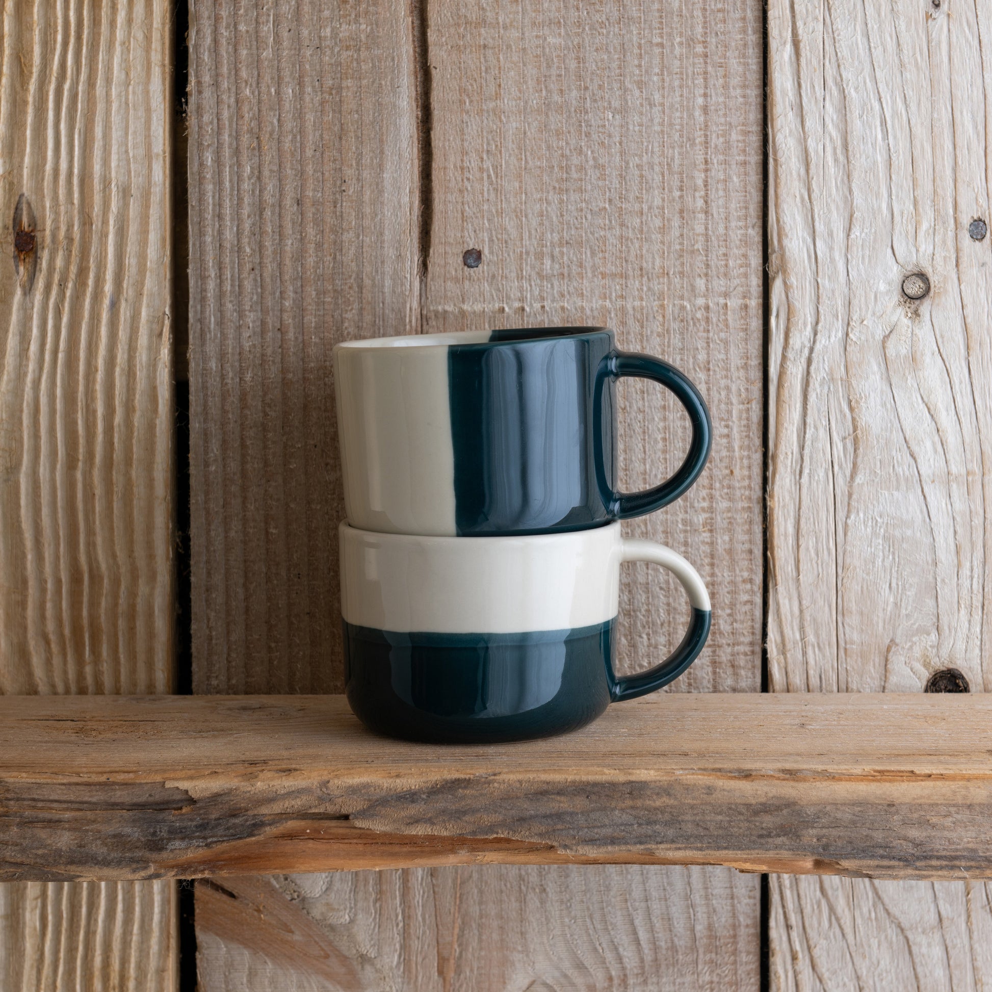 Sea green Rue mugs stacked on a weathered wooden shelf