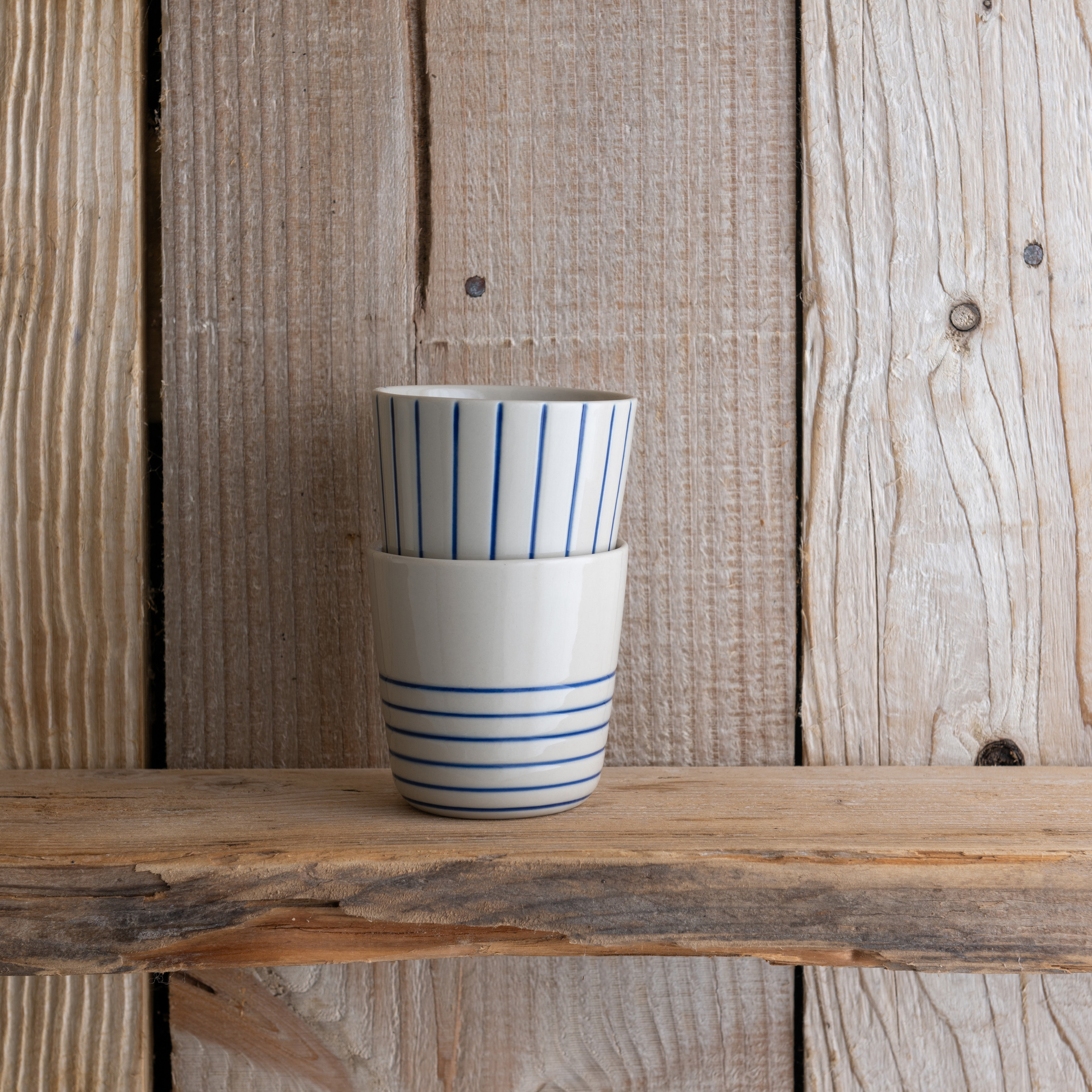 Indigo blue Sorrel beakers stacked on a weathered wooden shelf