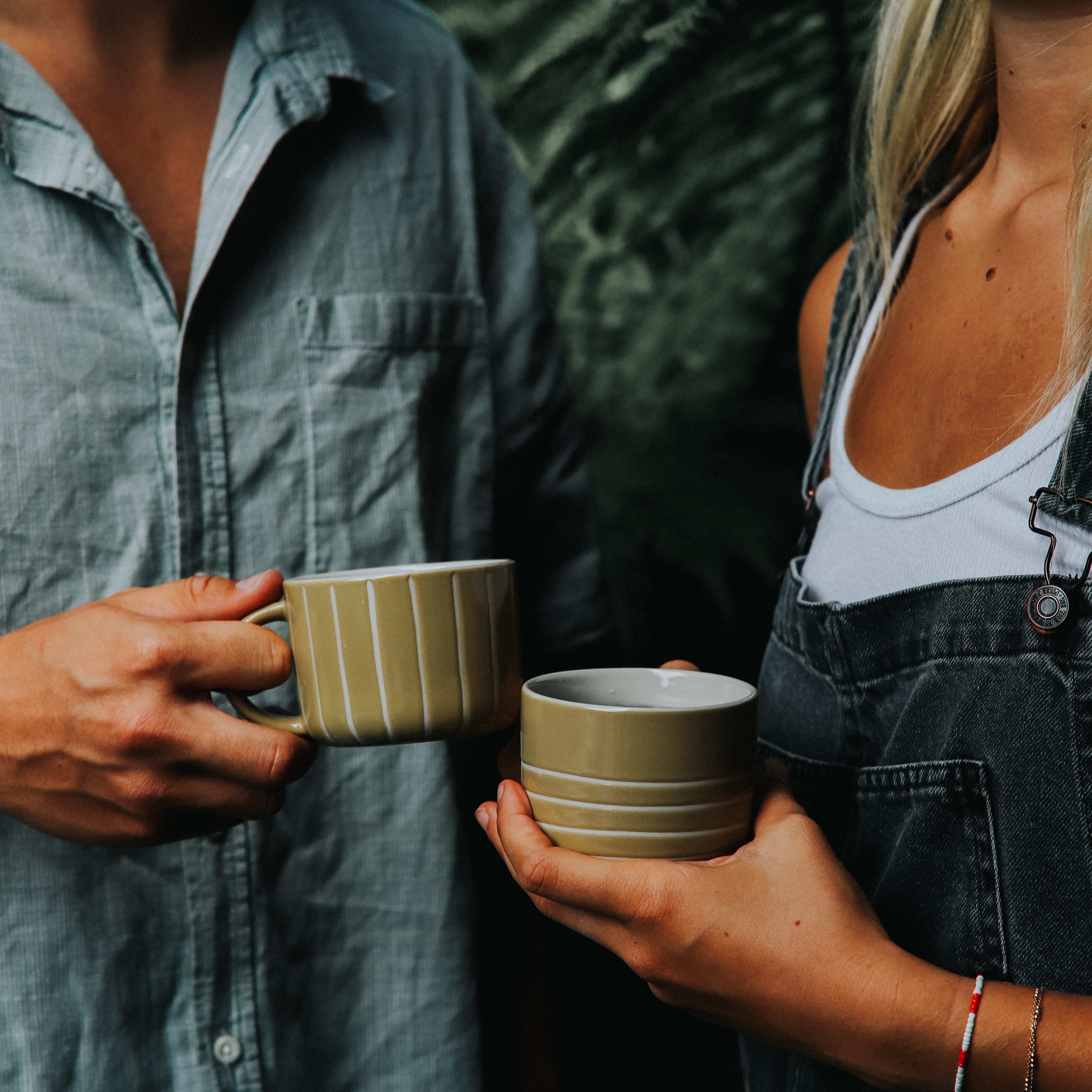 Two people holding mustard yellow Vervain mugs outdoors