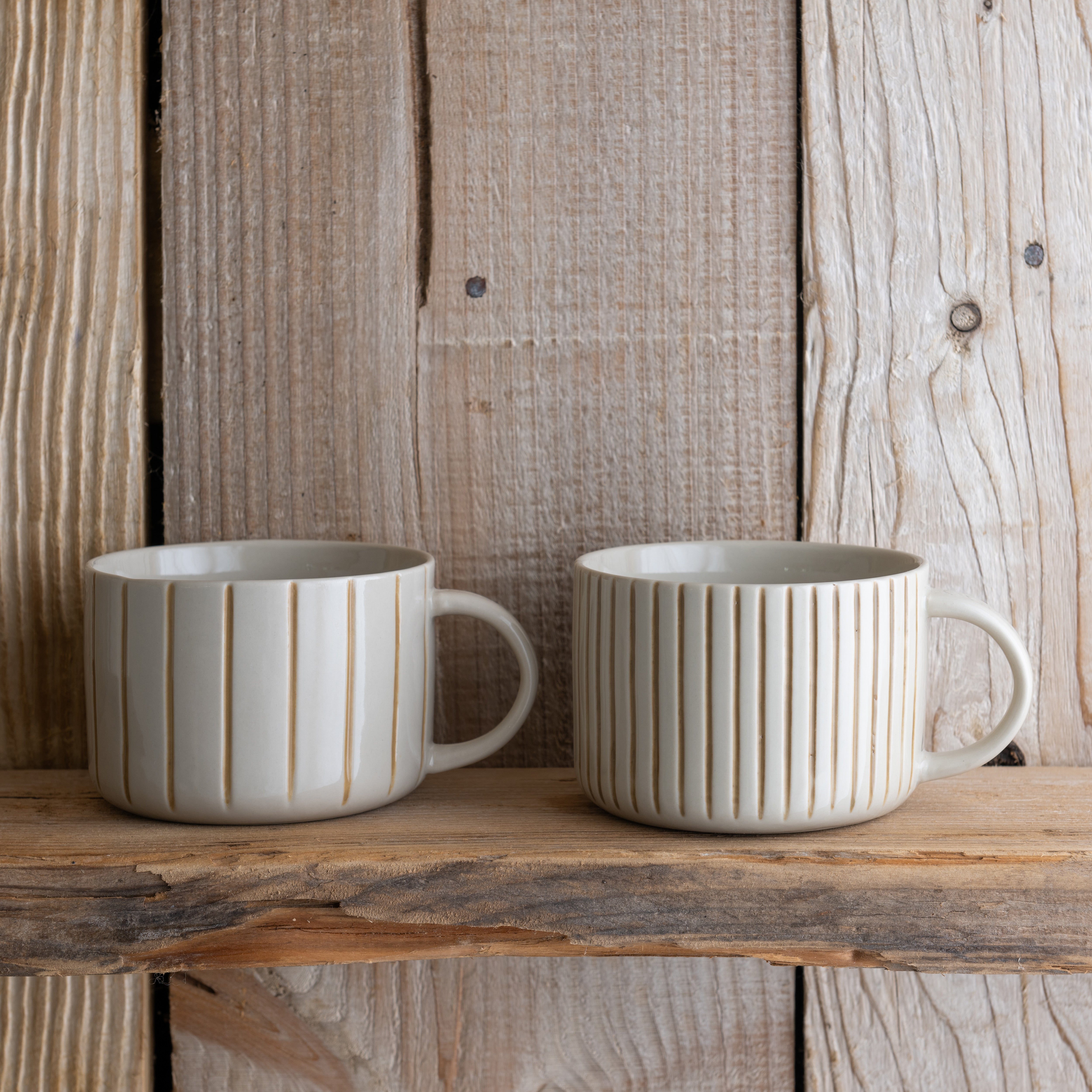 Two mustard yellow Yarrow mugs on a rustic wooden shelf