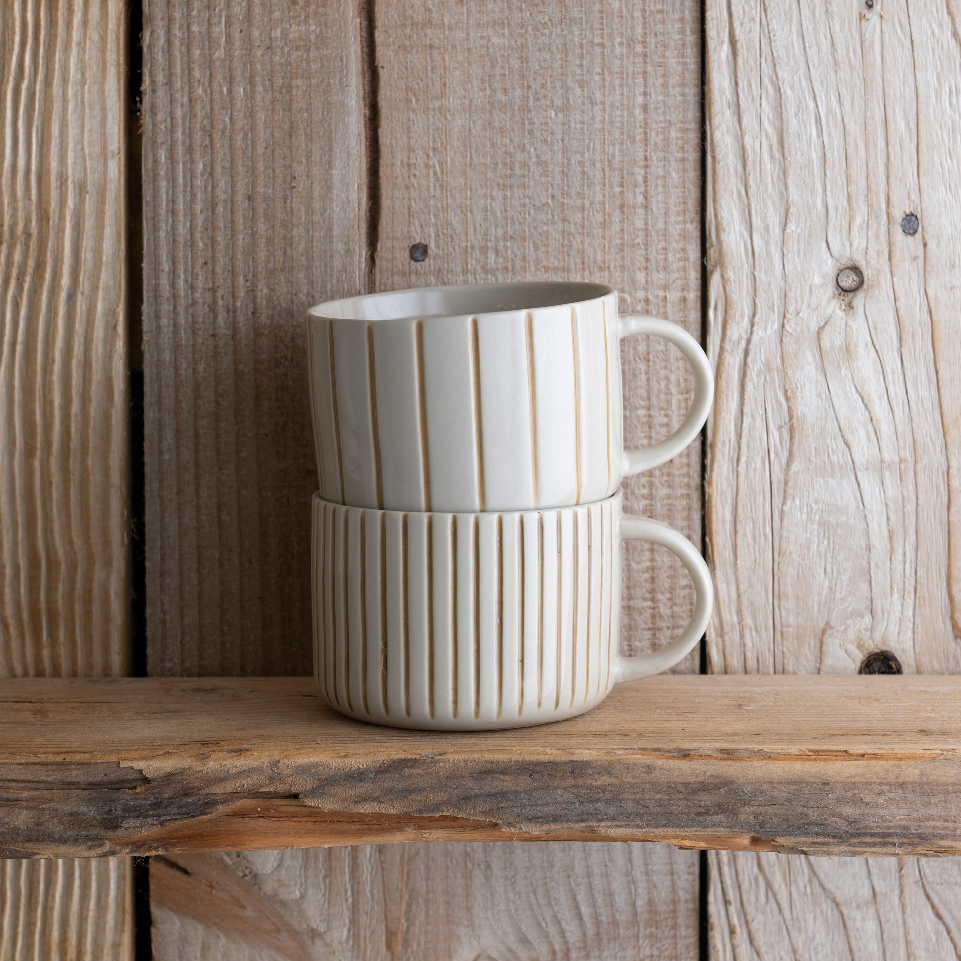 Mustard yellow Yarrow mugs stacked on a weathered wooden shelf
