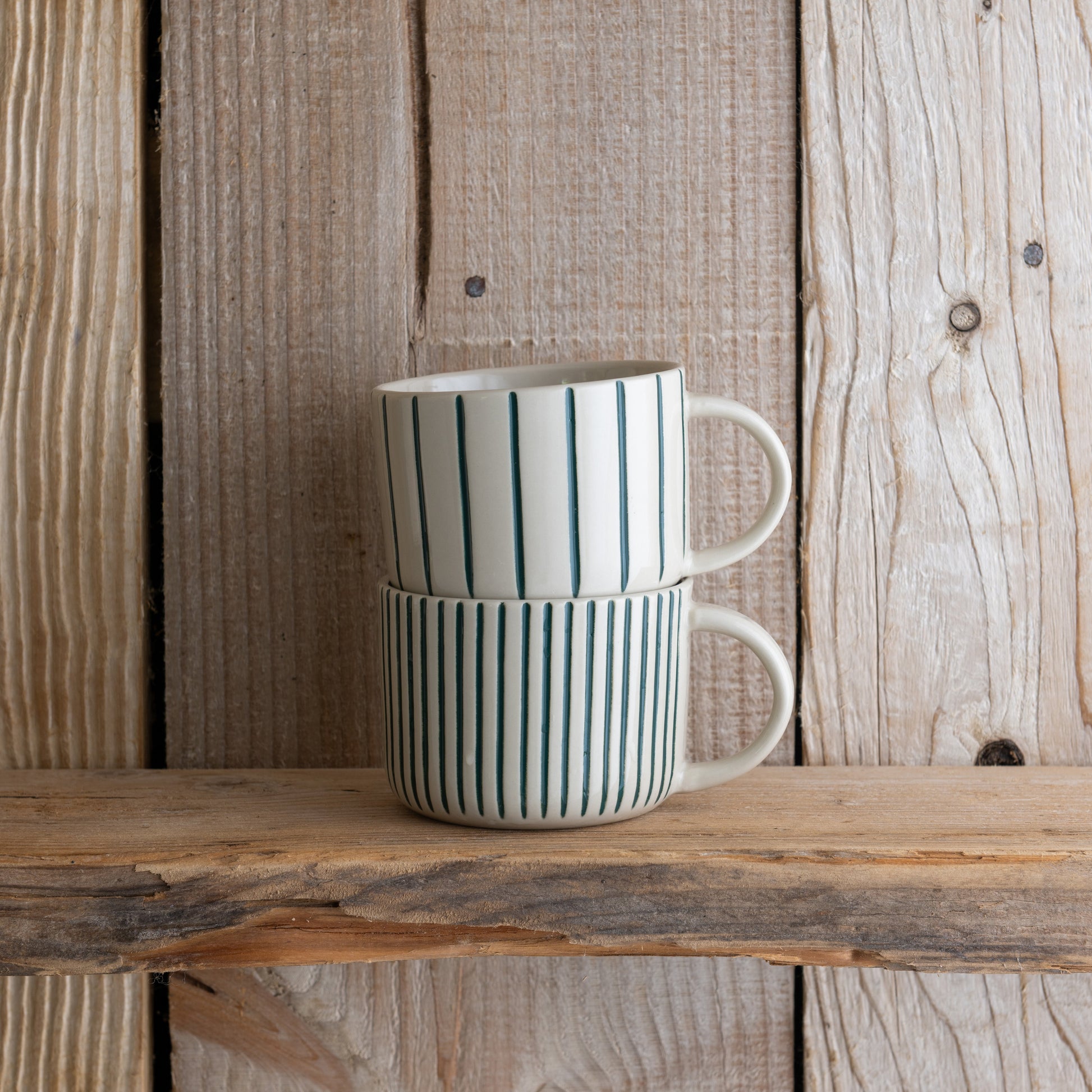 Sea green Yarrow mugs stacked on a weathered wooden shelf