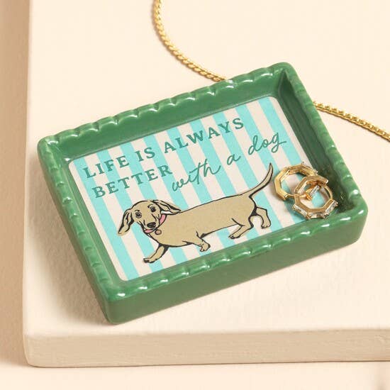 Ceramic trinket dish with dachshund design and striped background holding gold earrings.