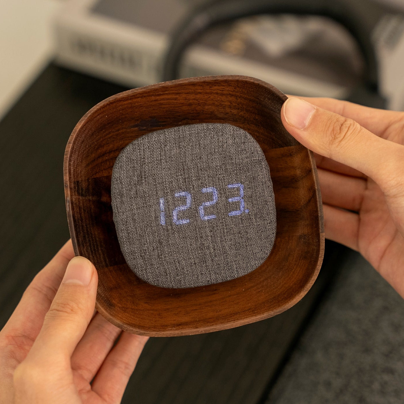 Hands holding square walnut Lumos clock with display