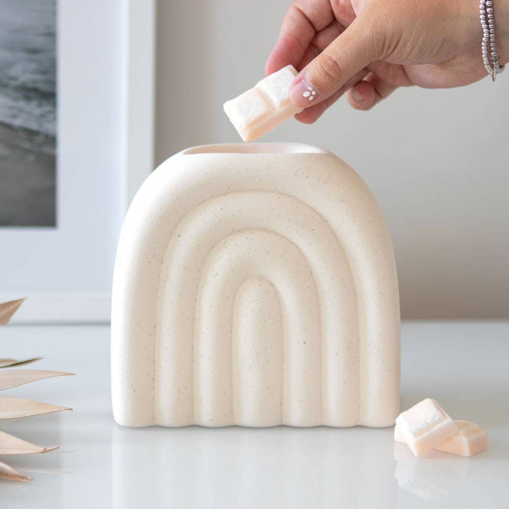 Cream speckled arch oil burner on shelf in minimalist setting