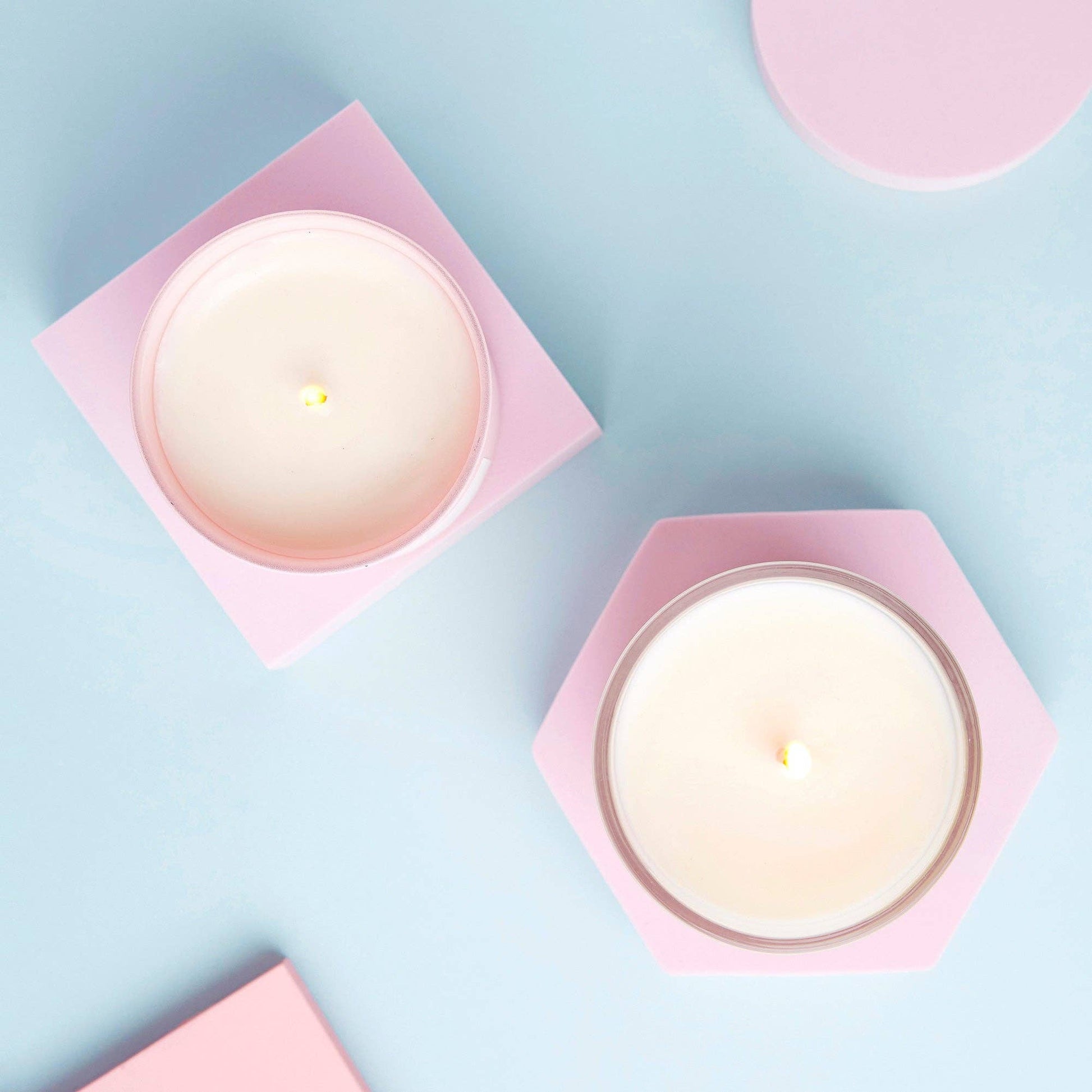 My Last Fuck candles seen from above in pink holders on a pale blue surface