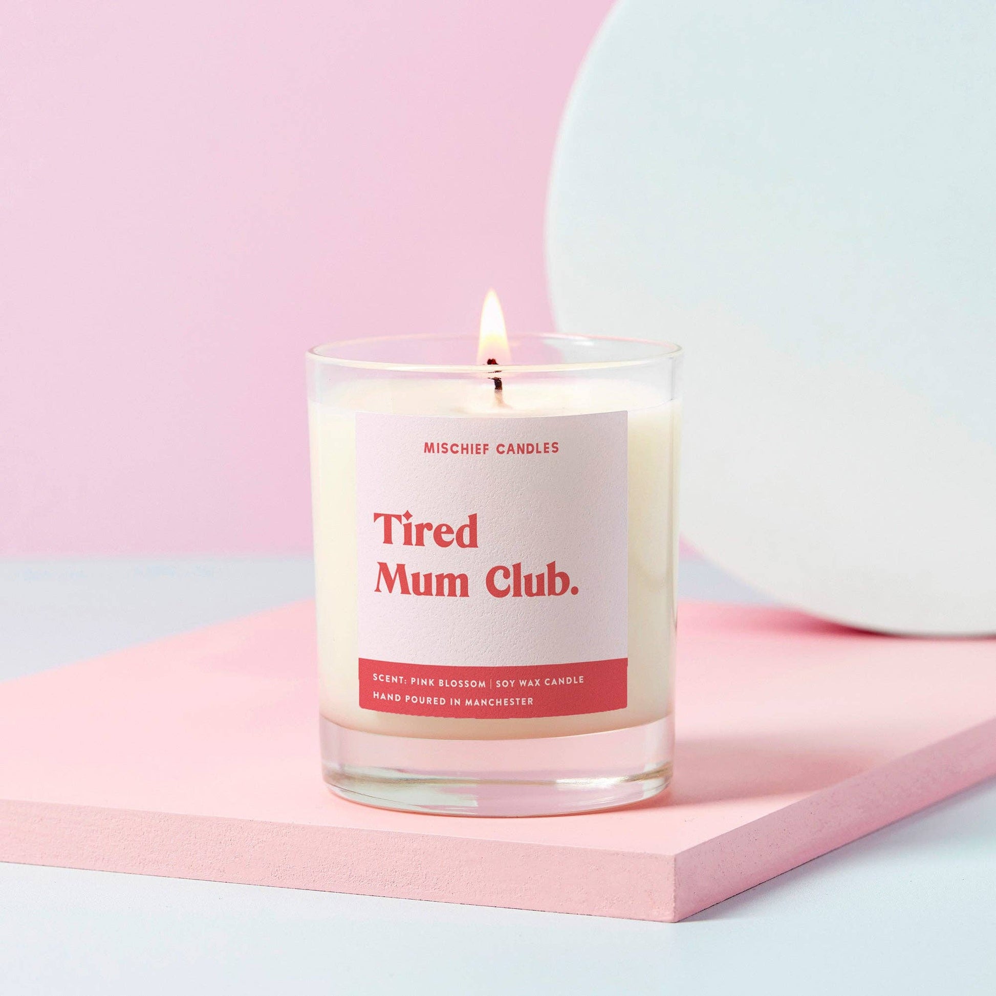 Tired Mum Club candle lit in clear glass with Pink Blossom label