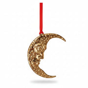 Gold aluminium crescent moon with a face on red velvet, hanging on a tree