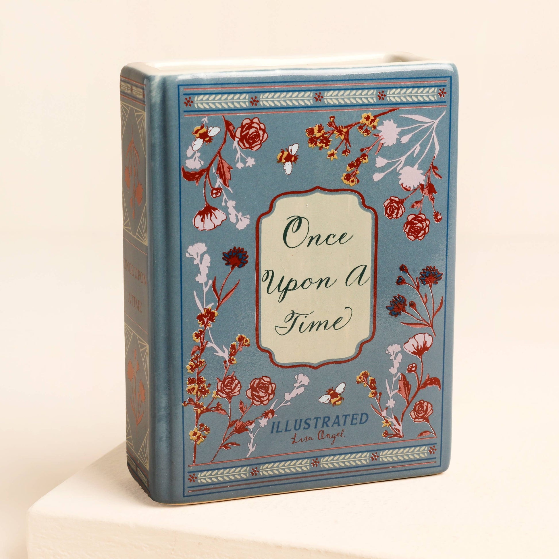 Blue ceramic book vase with floral illustration and vintage-style crest.