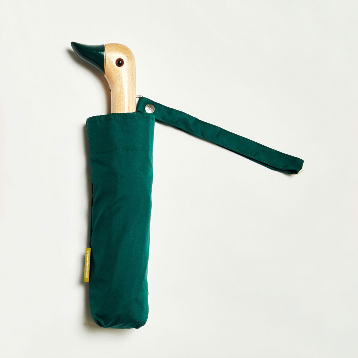 Closed forest green duck umbrella flat lay showing duck head handle and strap