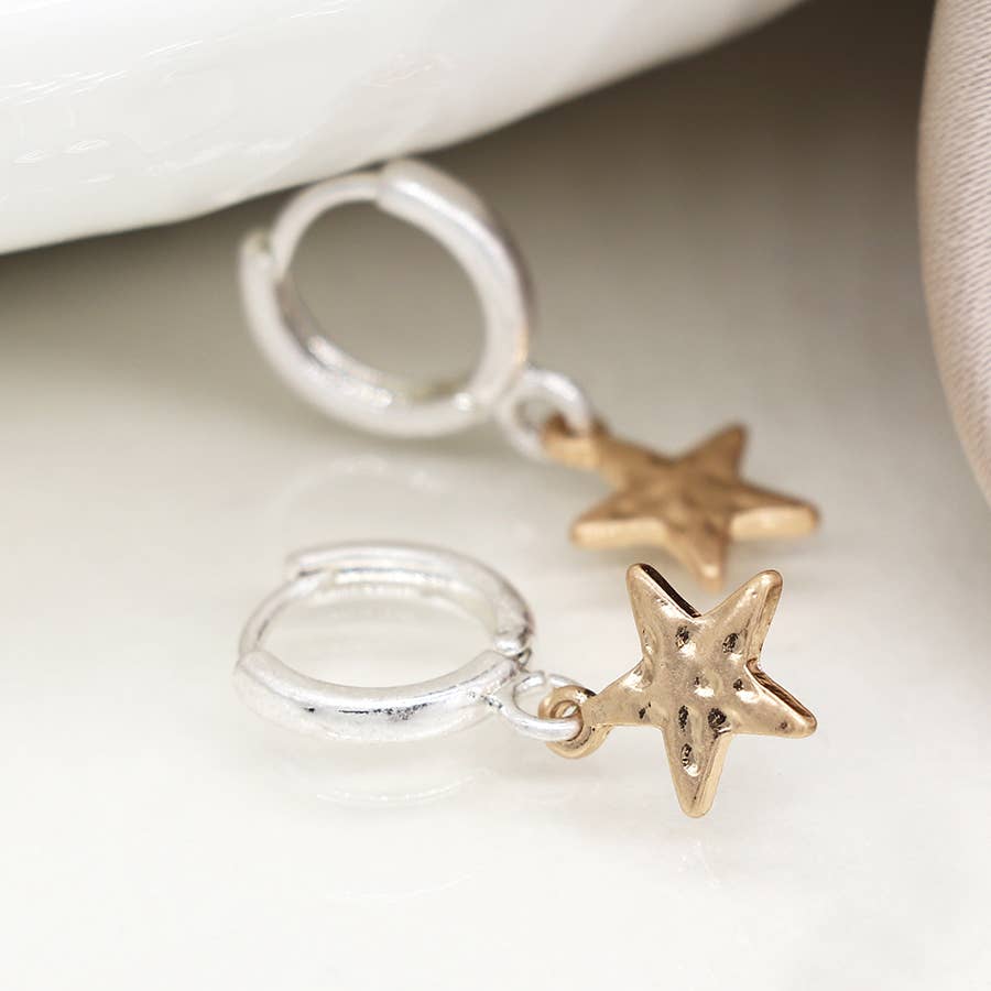 Silver hoops with gold star charms on white fabric