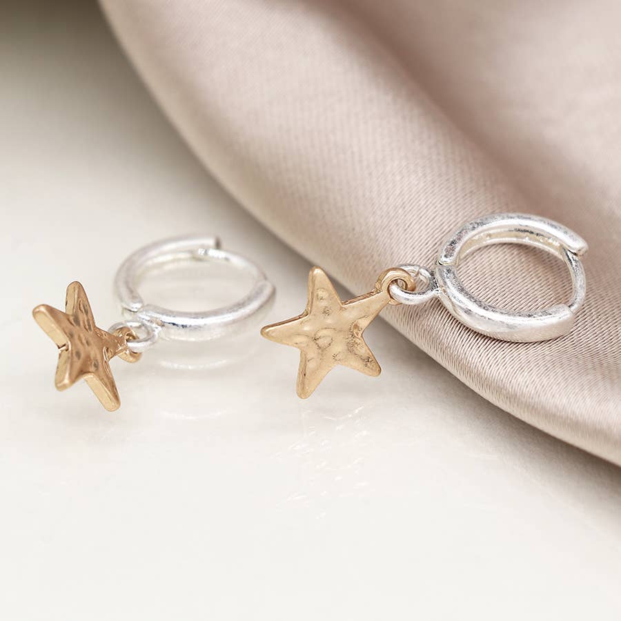 Silver hoop earrings with gold stars on soft beige satin