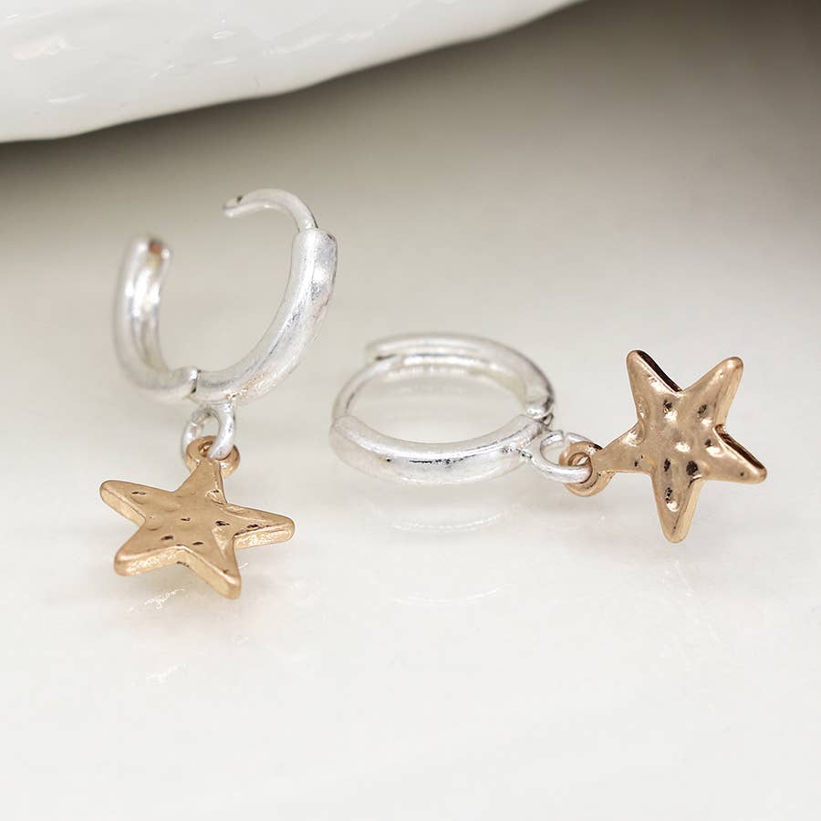 Silver hoop earrings with hammered gold star charms on a white surface